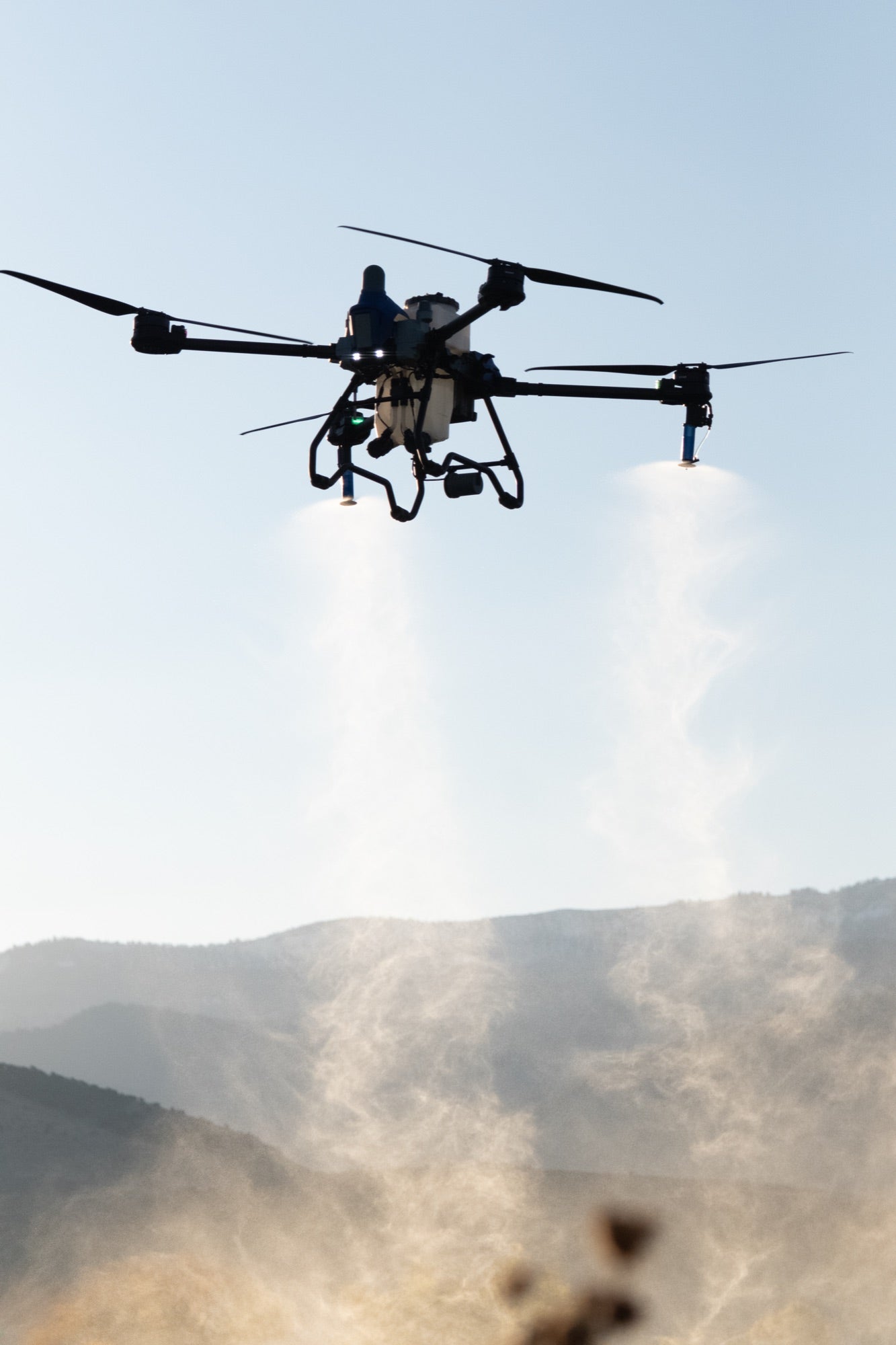 EAVision J70 spray drone spraying in flight, twin spray plumes drifting below the aircraft