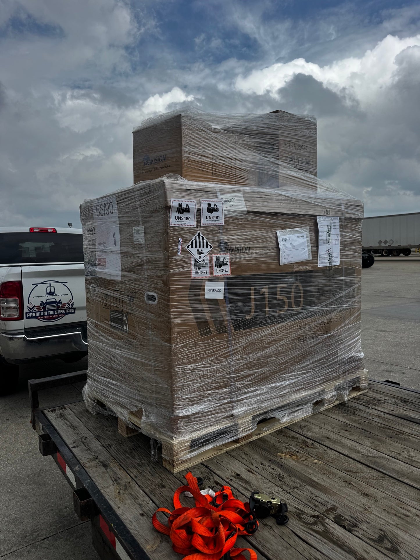 Crated EAVision J150 spray drone strapped to a Premium Ag Services trailer at a freight terminal, ready to be delivered to the customer