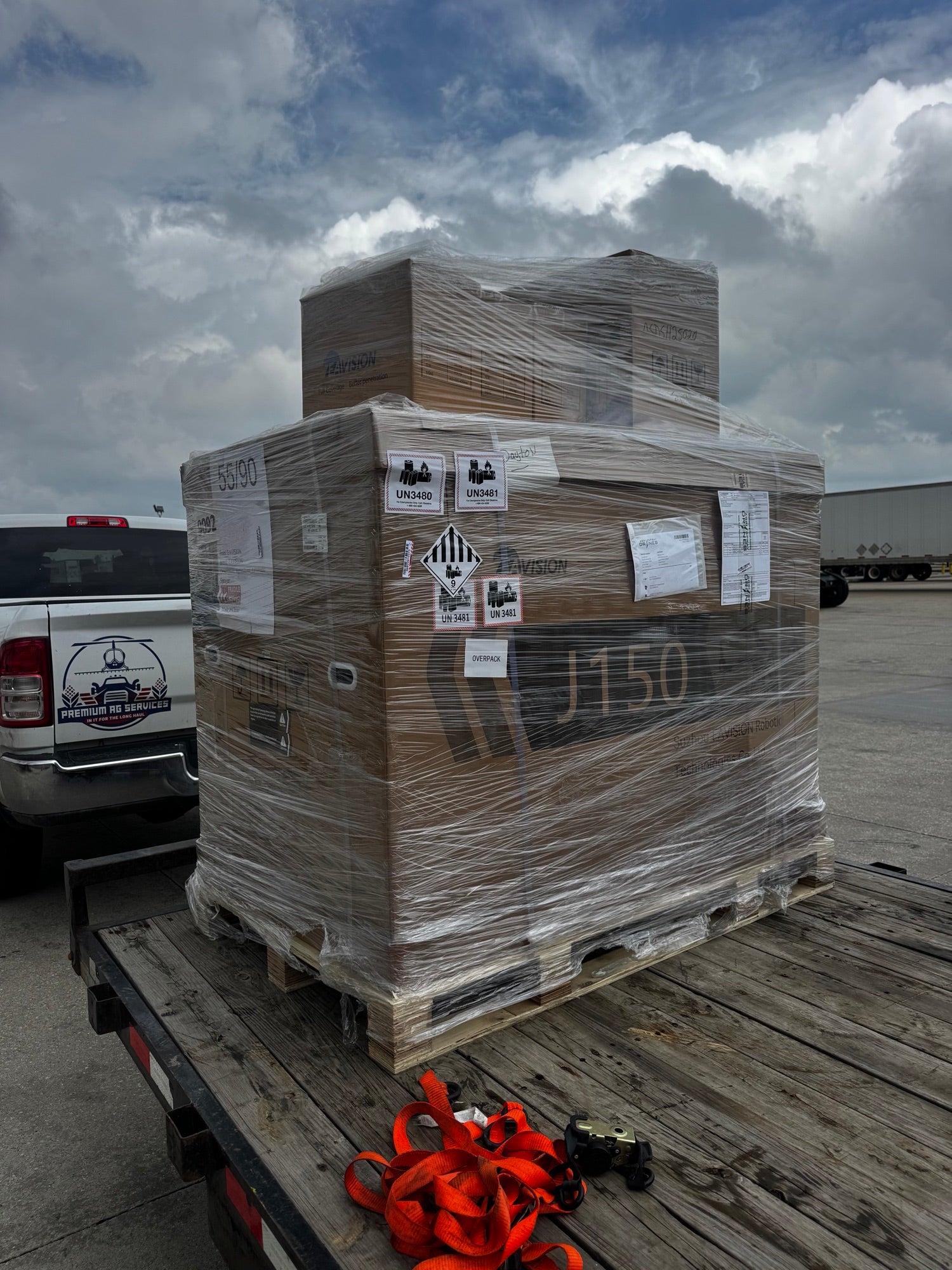 Crated EAVision J150 spray drone strapped to a Premium Ag Services trailer at a freight terminal, ready to be delivered to the customer